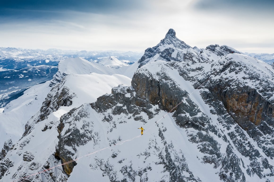 Nathan Paulin sur une corde au milieu de deux massifs alpins