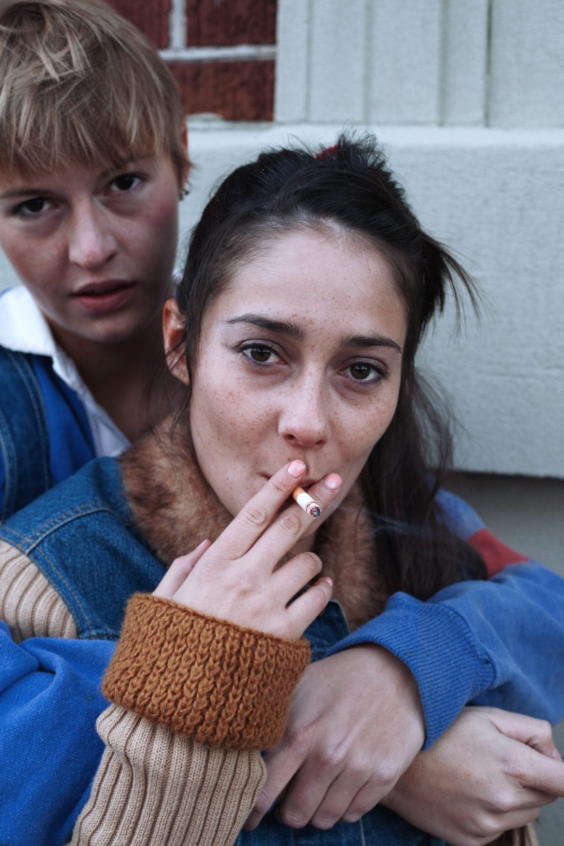 photo d'un couple avec une femme qui fume dans les bras de sa partenaire 