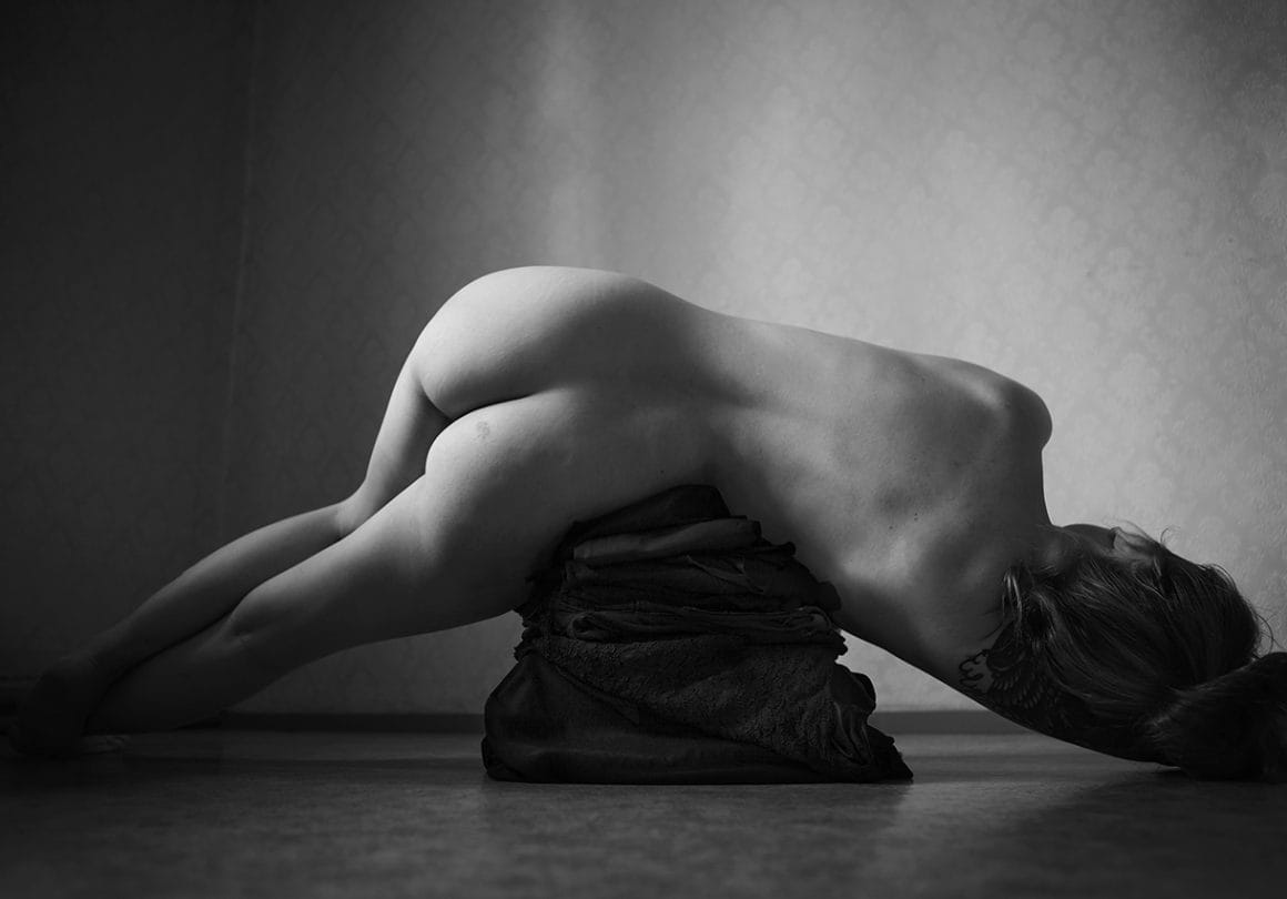 Hilla Kurki nue couchée sur un tas de tissus noir 