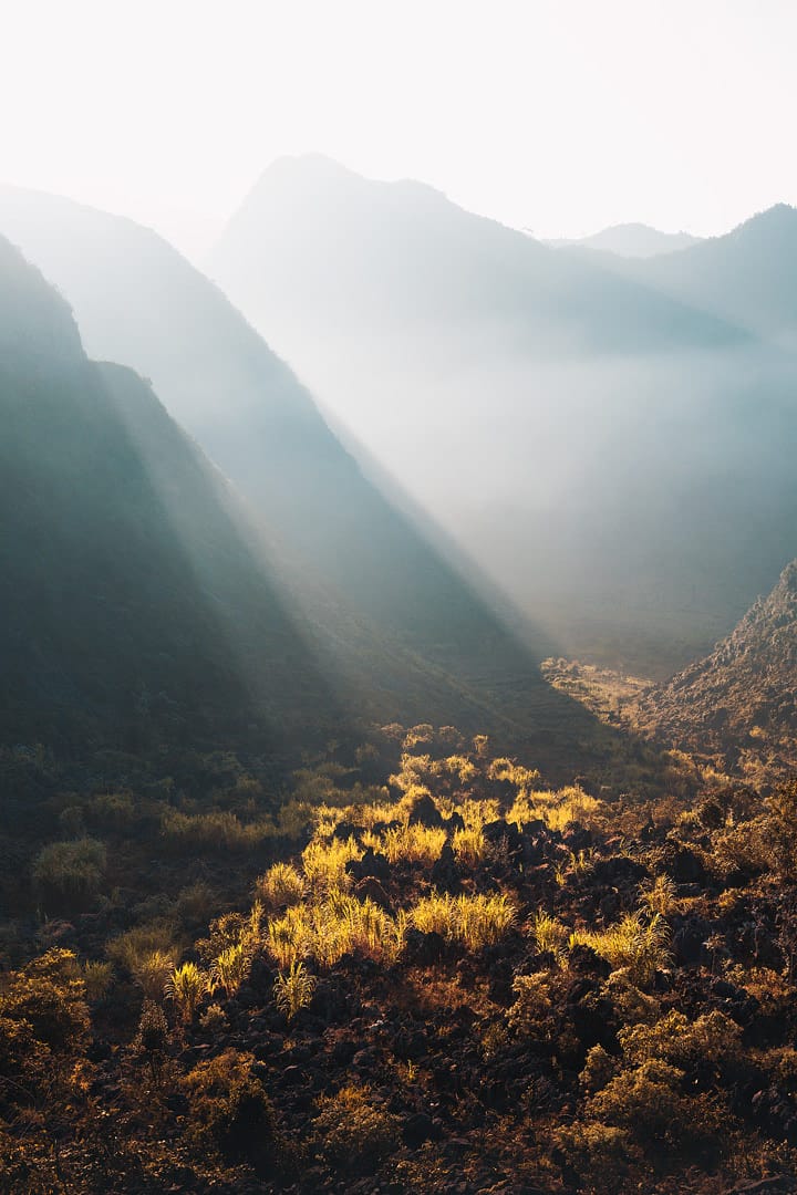 Voici une des impressionnantes photographies de Lukas Furlan : 
Vu sur le sol d'une montagne éclairé par des faisceaux de lumière du soleil et encadré d'autres montagnes. 