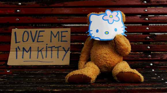 Epidemic Happiness est une oeuvre de Biancoshock qui représente un ourson en peluche avec une pancarte "Love me I'm Kitty". 
