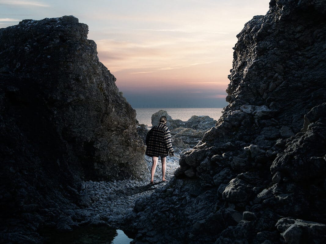 Kristoffer Axén, un personnage sur la plage entre deux rochers. 