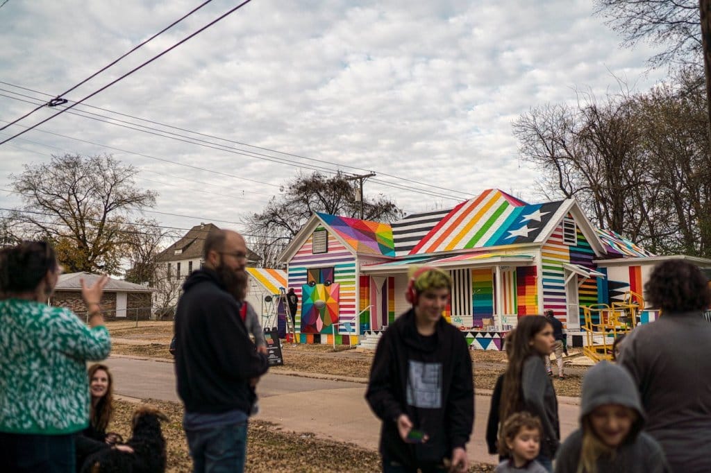 Photo de la maison peinte par Okuda dans l'Arkansas. On y voit les habitants du quartier qui suivent l'avancée du projet. 