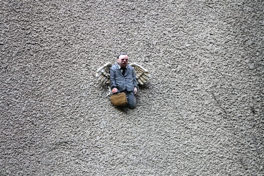 Isaac Cordal, une home miniature portant des ailes semblent sortir du béton. 