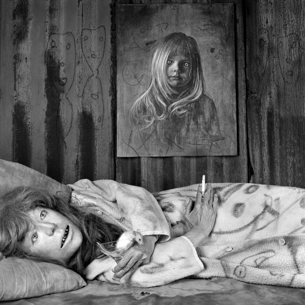 Une femme inquiétante couchée sous un portrait inquiétant. 