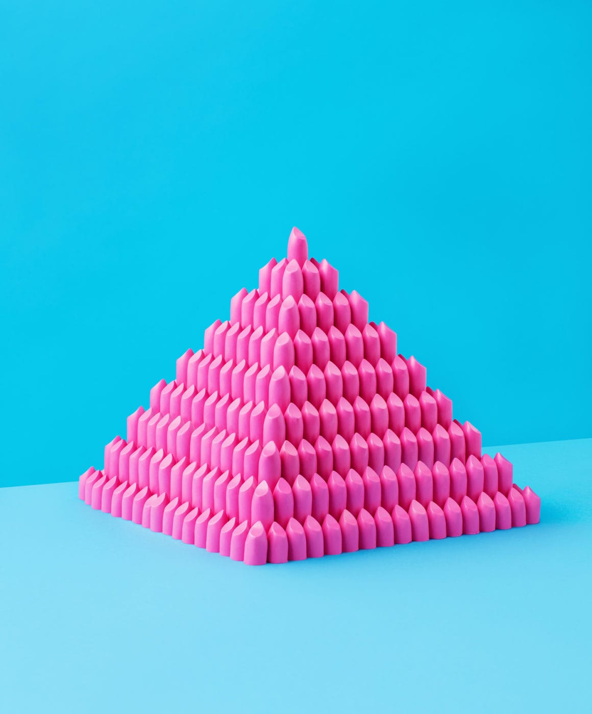Une pyramide de rouge à lèvre rose sur fond bleu. 