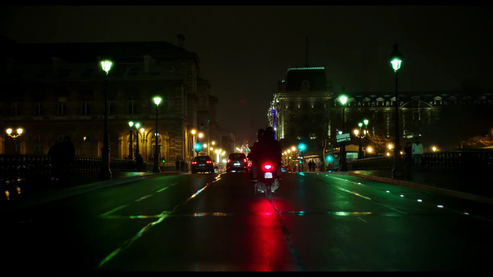 Vue de nuit sur une rue parisienne, un scooter et des véhicules freinent