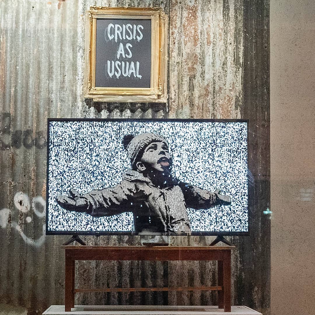 Boutique éphémère de Banksy, un écran affiche un pochoir d'un enfant et un tableau affiche le slogan "crisis as usual"