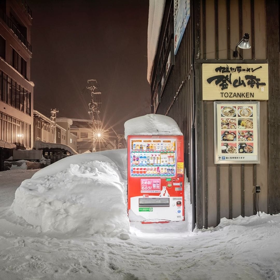 Un distributeur automatique couvert de neige est à côté d'un restaurant
