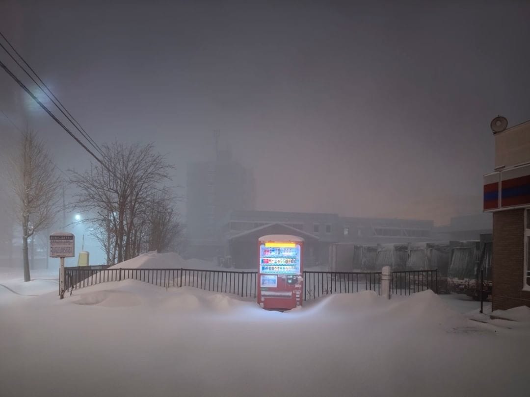 Dans un paysage brumeux et enneigé se détache un distributeur lumineux