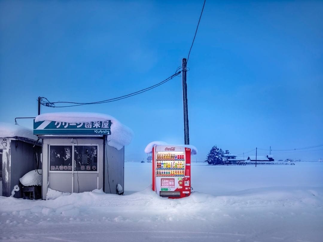 Dans la campagne ensevelie par la neige, un distributeur est allumé