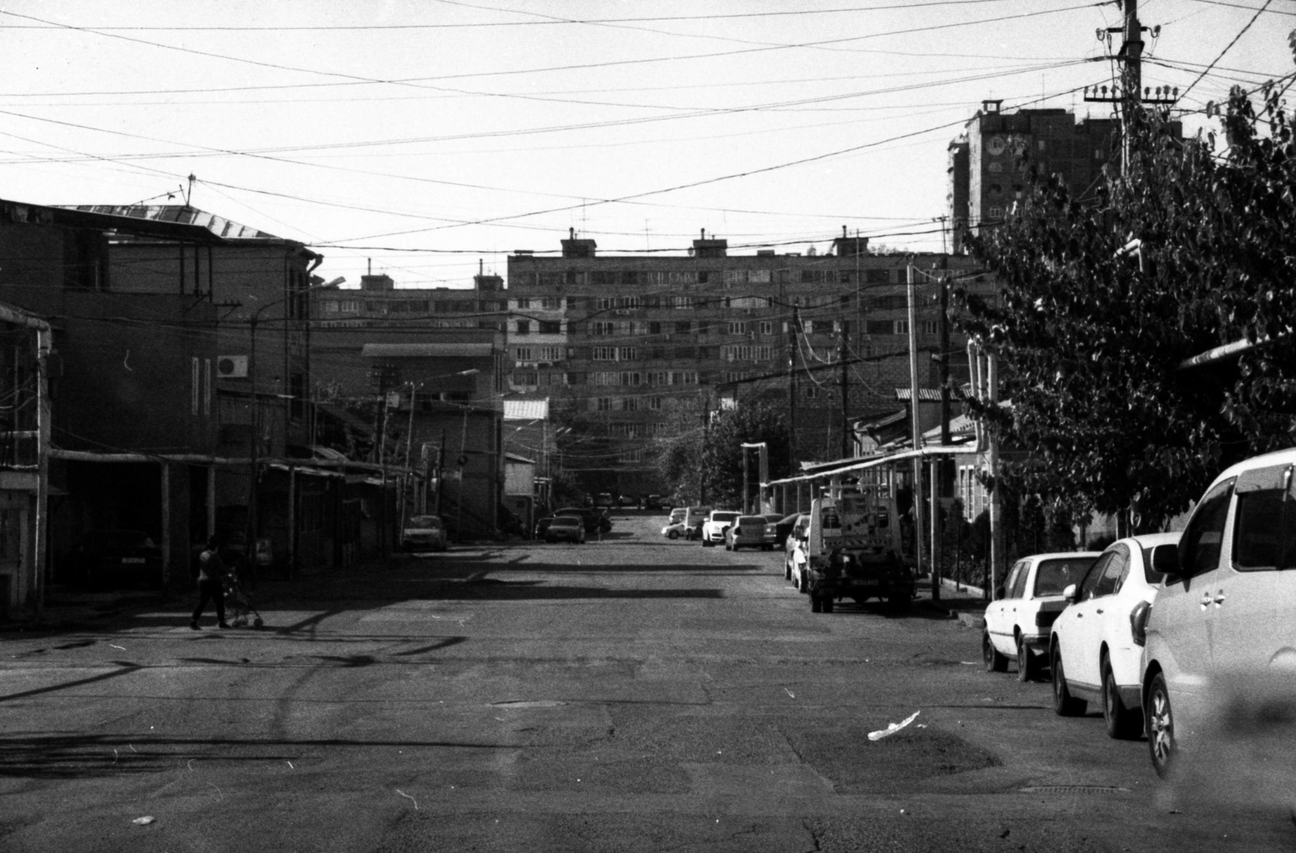 Photographie en noir et blanc d'une rue dans laquelle il n'y a aucune trace d'être humain, comme si le paysage urbain avait été vidé des hommes.