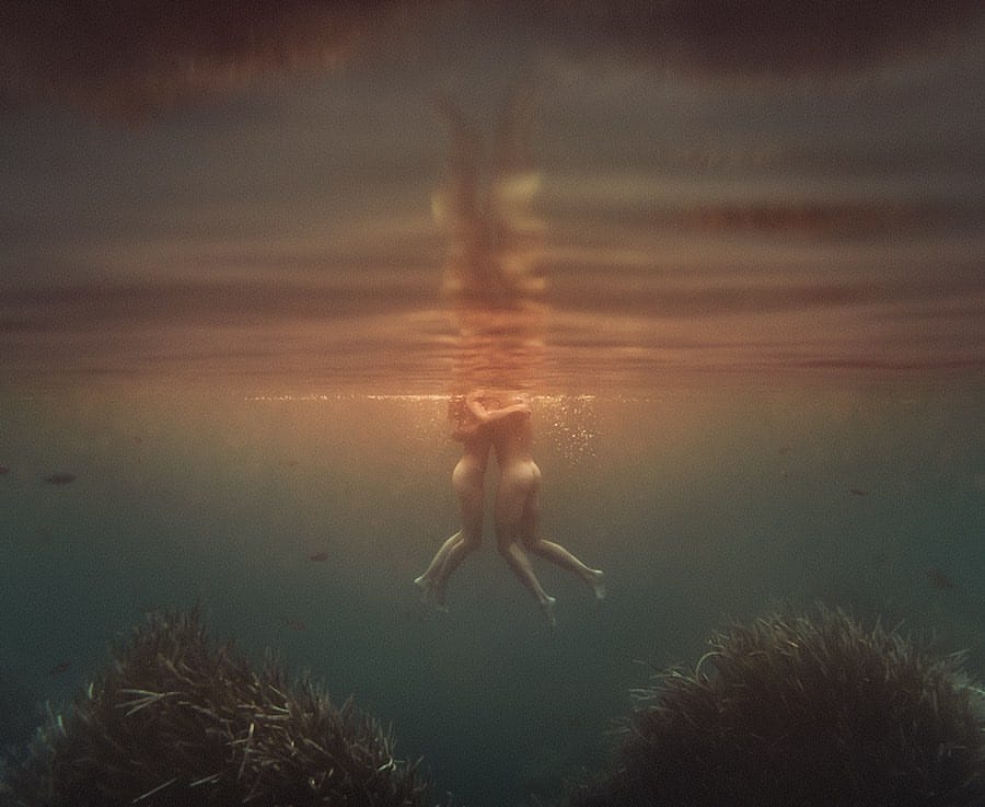 Photographie prise sous l'eau, on voit le corps d'un homme et le corps d'une femme qui se tiennent. Ils n'ont pas pieds.