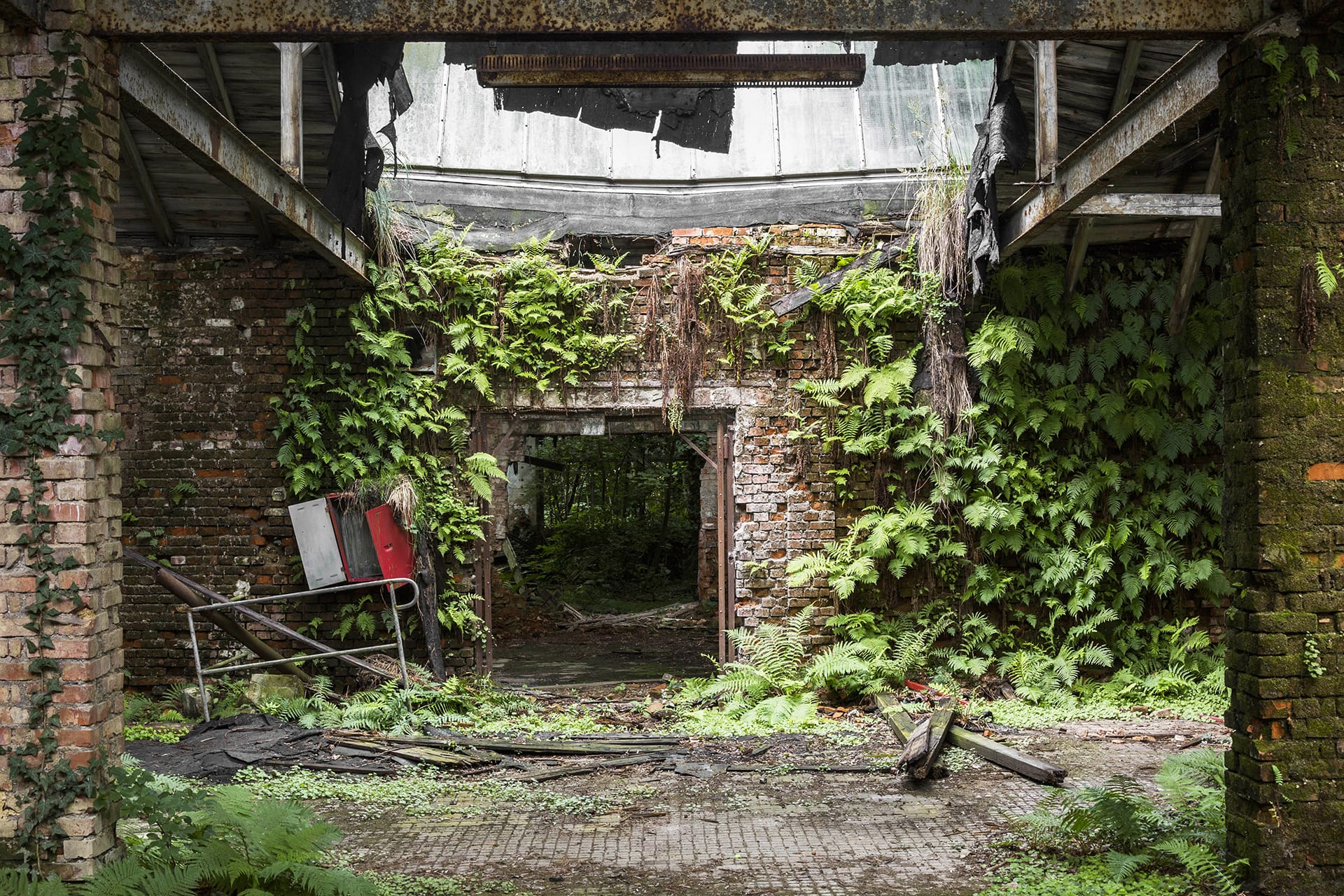 Porte d'une usine, les murs en brique sont recouverts de plantes