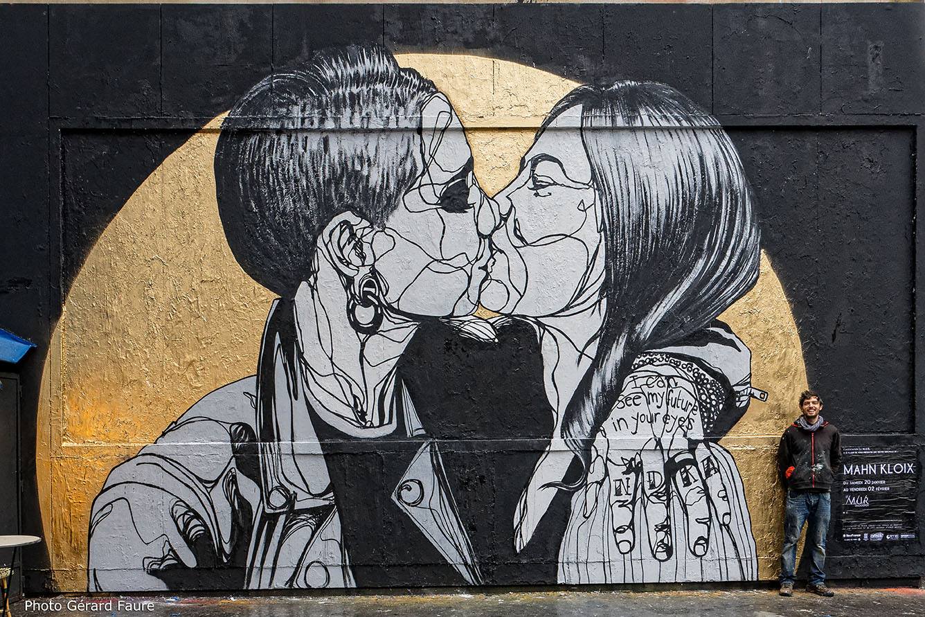 Sur un fond en cercle doré, deux personnes en noir et blanc s'embrassent. Leur peau est parcourue de lignes noires.