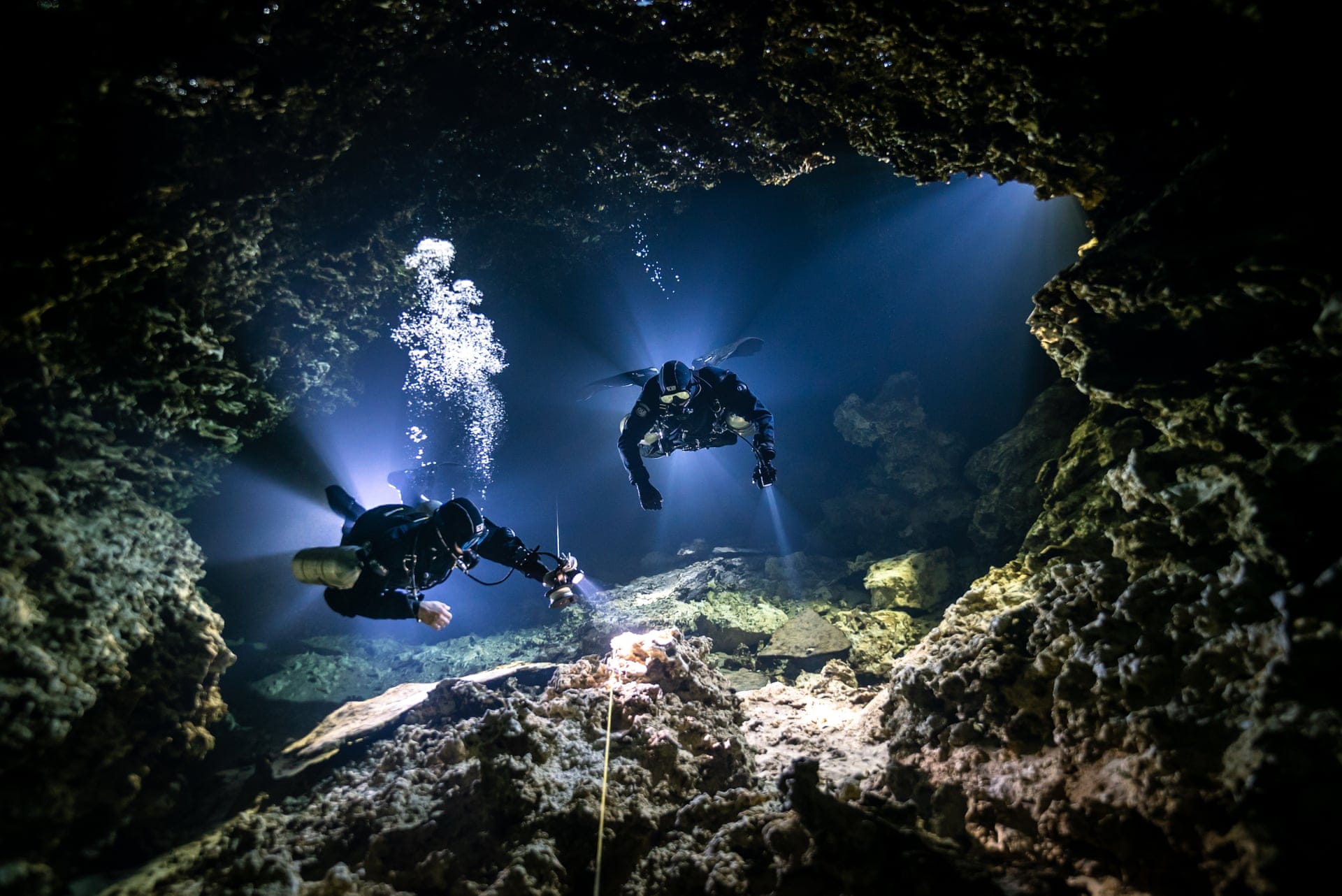 Plongeurs qui observent une grotte sous-marine obscure