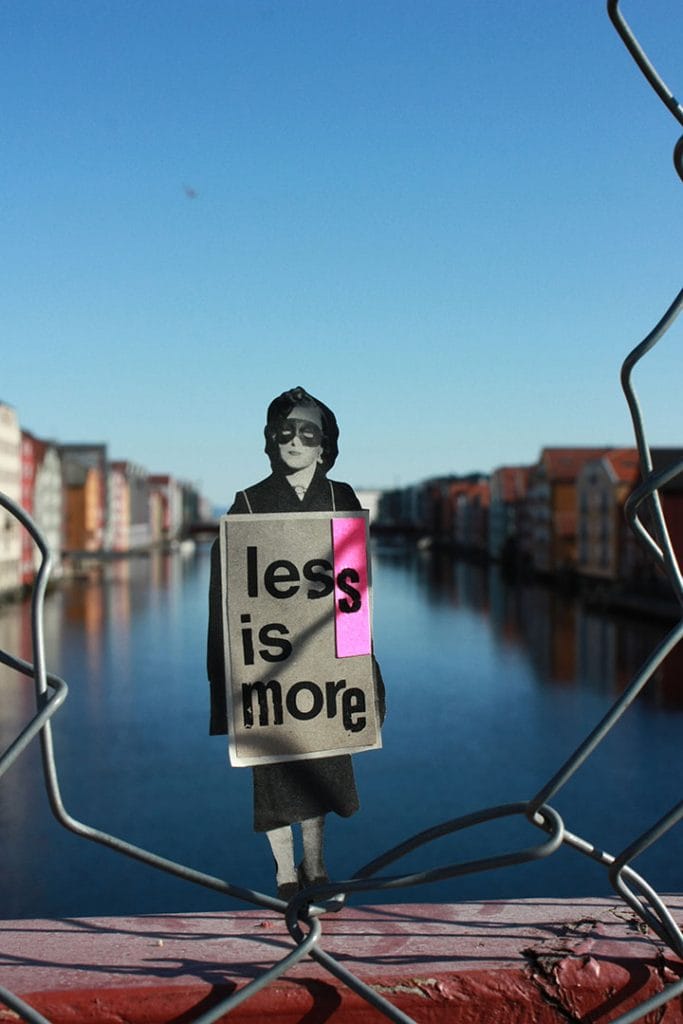 Une femme avec une pancarte "less is more" posant sur un pont