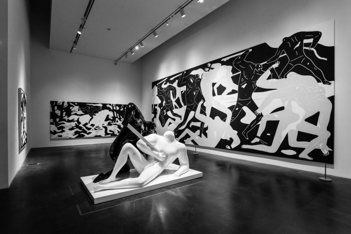 Vue de l'exposition "The Shadow of Men" - Trois peintures de formats variés encadrent une statue d'un homme noir qui blesse un homme blanc avec un bâton blanc au torse.
