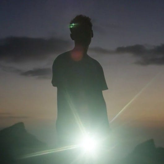 Silhouette d'un homme sur fond coucher de soleil. Flash aveuglant en bout de bras, effet de lumière sur la silhouette sombre.
