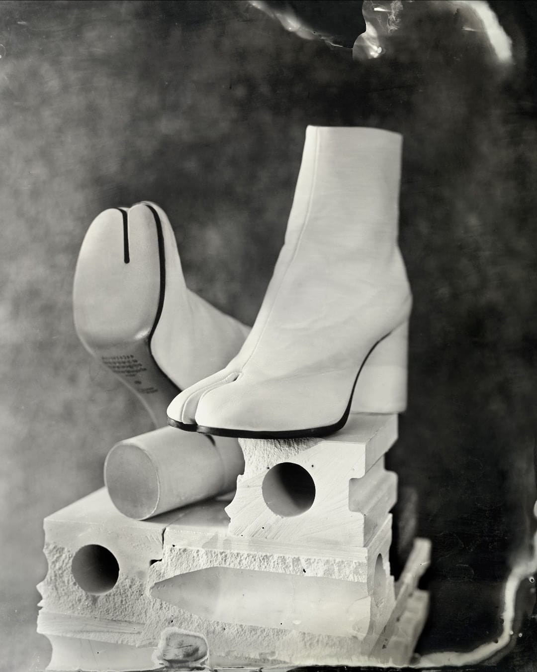 Bottines Tabi par Maison Margiela : bottine blanche à semelle noire, talon rond. À l'avant, au niveau des orteils, la chaussure est divisée en deux, presque comme une paire de tongues. 