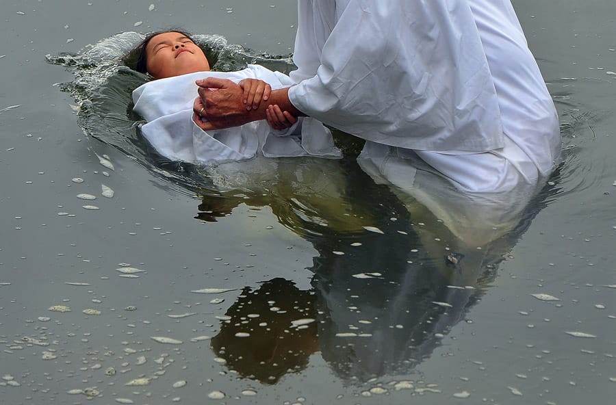 Une jeune fille est baptisée dans une rivière.