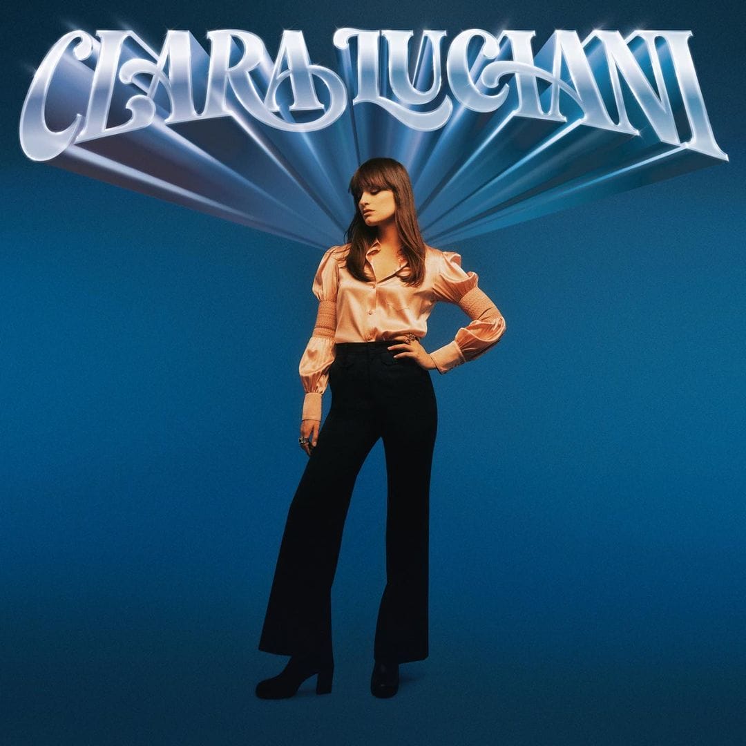 Pochette de l'album coeur, le nom de Clara Luciani est écrit en gros en haut sur un fond monochrome bleu. La chanteuse s'y distingue, en posant la main sur la hache et le regard baissé.