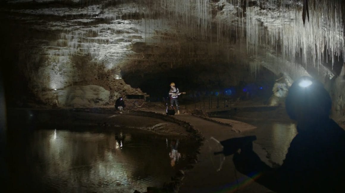 Au coeur d'une grotte, Myd joue de la guitare pendant que les deux autres enregistrent le son à distance.