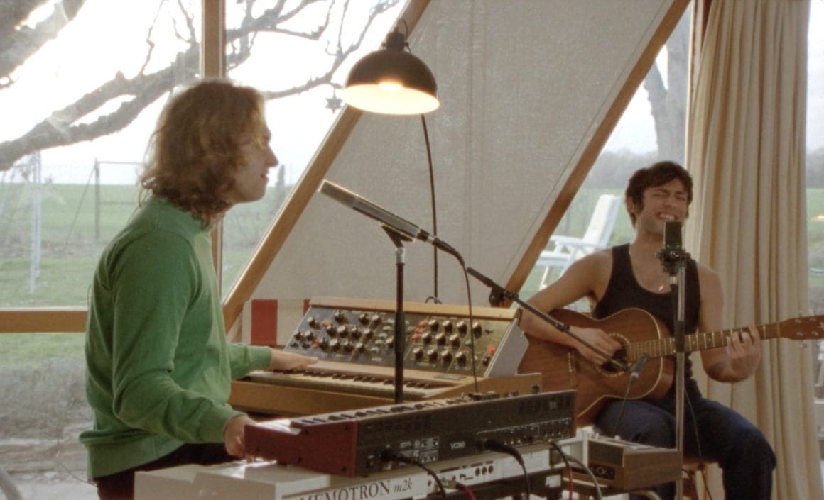 Plan avec les deux musiciens. A gauche  Clément Savoye est aux claviers, à droite  Adrien Rozé joue de la guitare acoustique face à un micro.