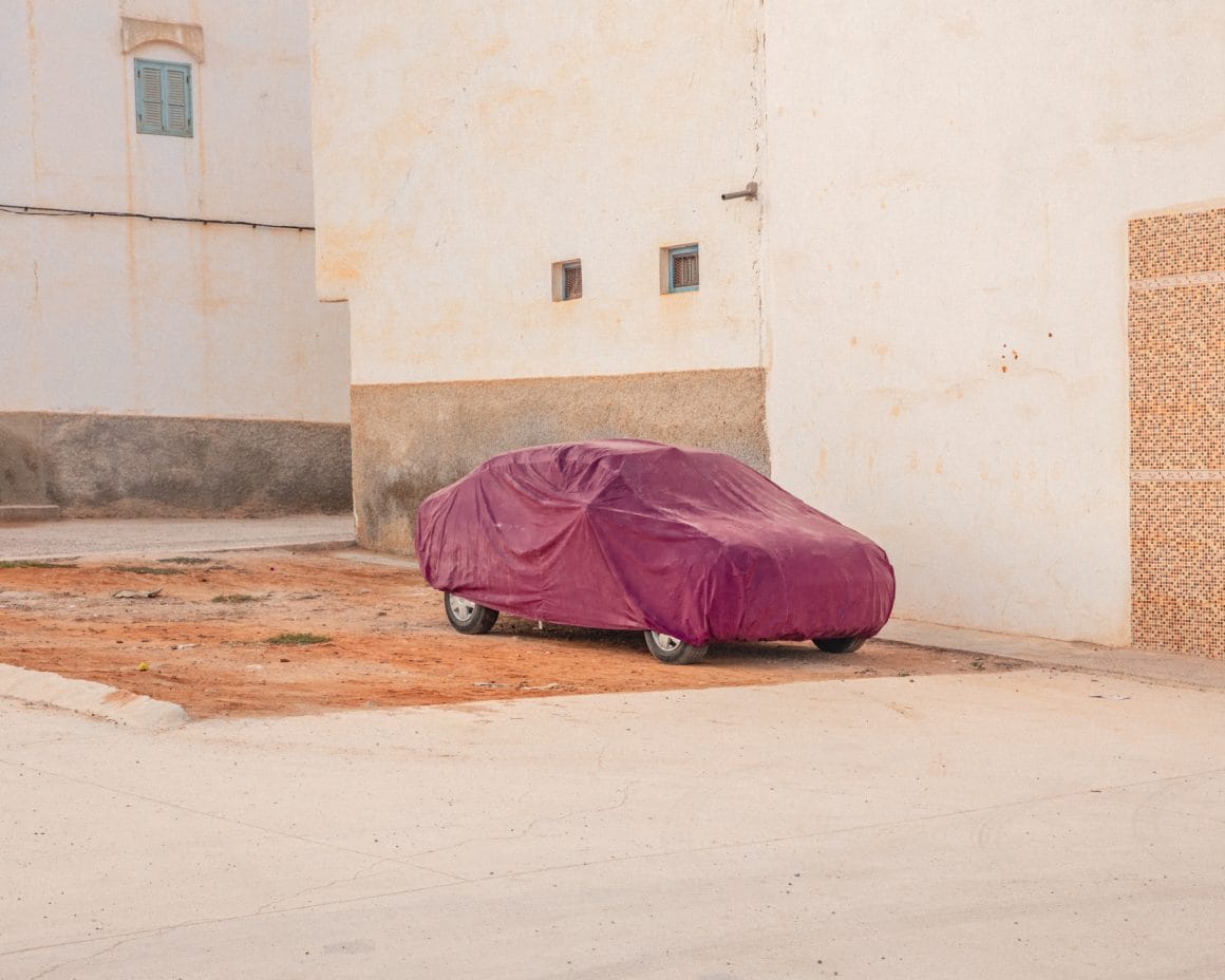 Photographie d'une voiture recouverte d'un drap rose.