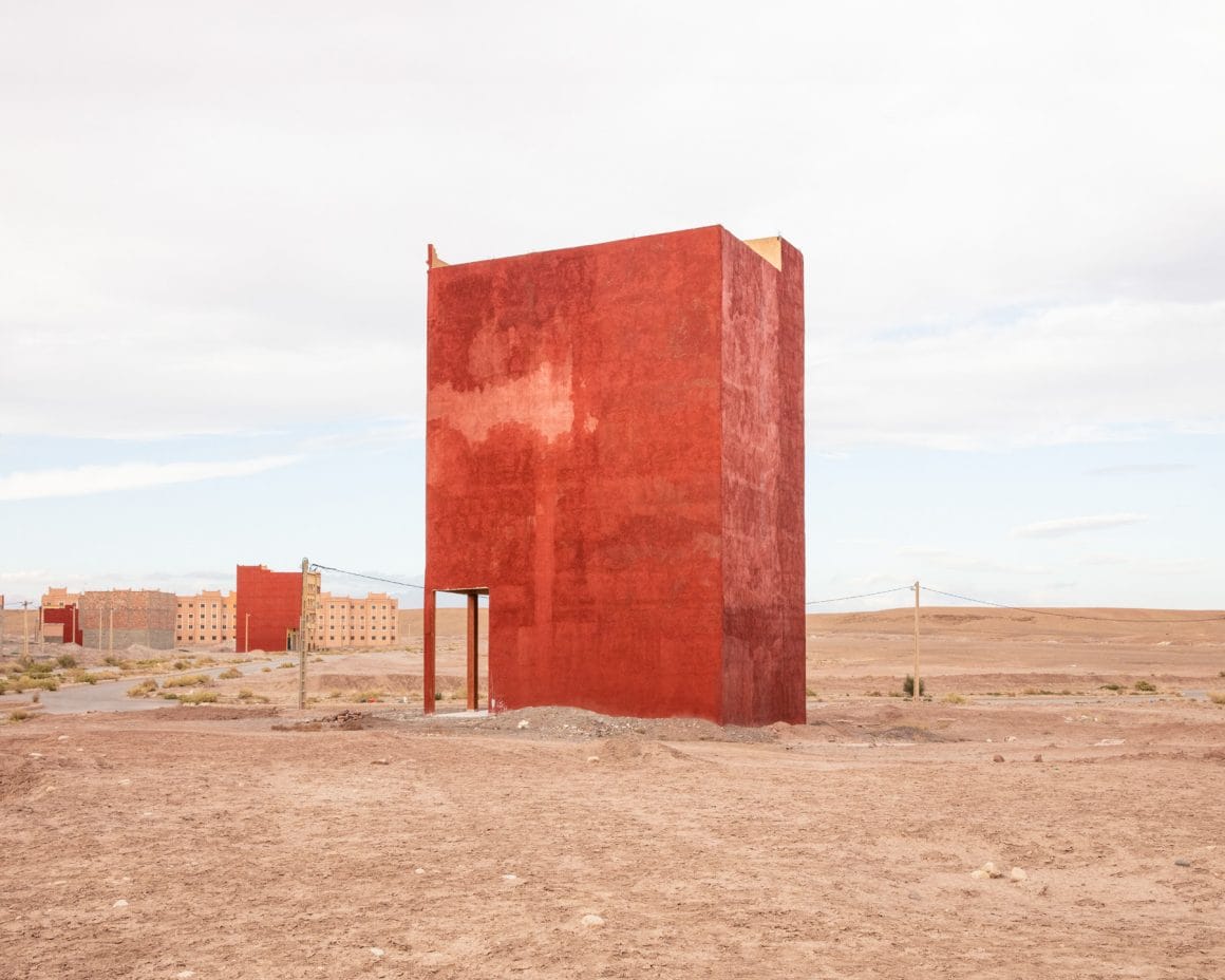 Photographie d'une structure inconnu au milieu du désert, en fond d'autres structures