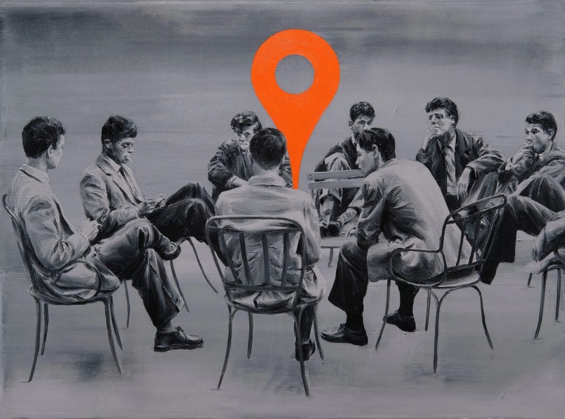 Groupe de jeunes hommes, assis en cercle. Au centre une grande épingle rouge de google maps.