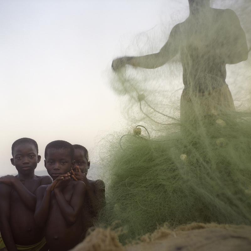 Photographie de trois enfants ghanéens et un filet de pêche.
