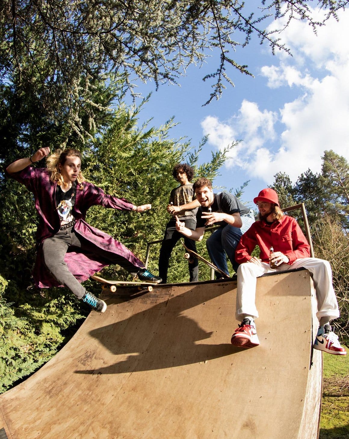Les membres du groupe Entropie, Adam, Bertrand, Loan et Valentin, sont regroupés sur un tremplin de skateboard au soleil.