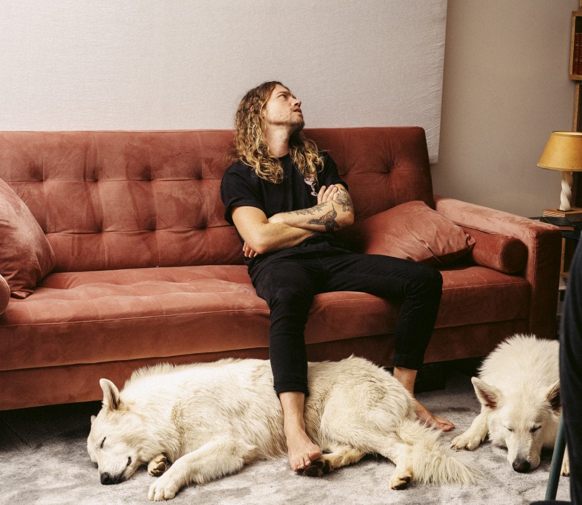 Julien Doré assis sur son canapé, en compagnie de ses deux chiens