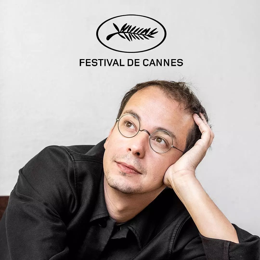 Portrait du musicien Rone, pose rêveuse la tête posée dans sa main. En fond, le logo du festival de Cannes.