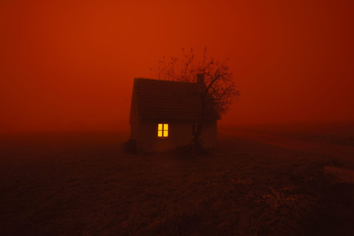 Photographie d'une maison isolée, le ciel est rouge.