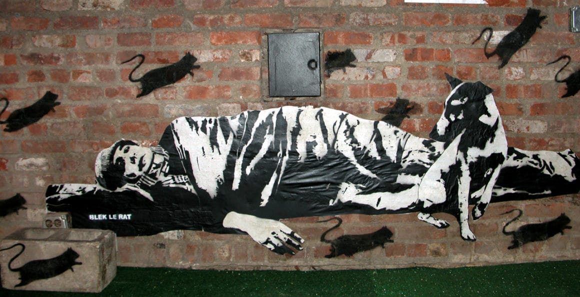 Un mendiant couché avec son chien infesté de rats peint au pochoir sur un mur de New York en 2005