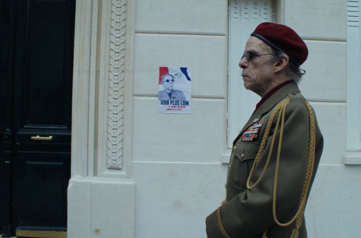 De profil, un dictateur âgé se tient dans la rue. Derrière lui, une affiche à son image : "Voir plus loin". Il porte sur le nez des lunettes, références aux "lunettes spéciales" qui reviennent régulièrement dans "écran total".