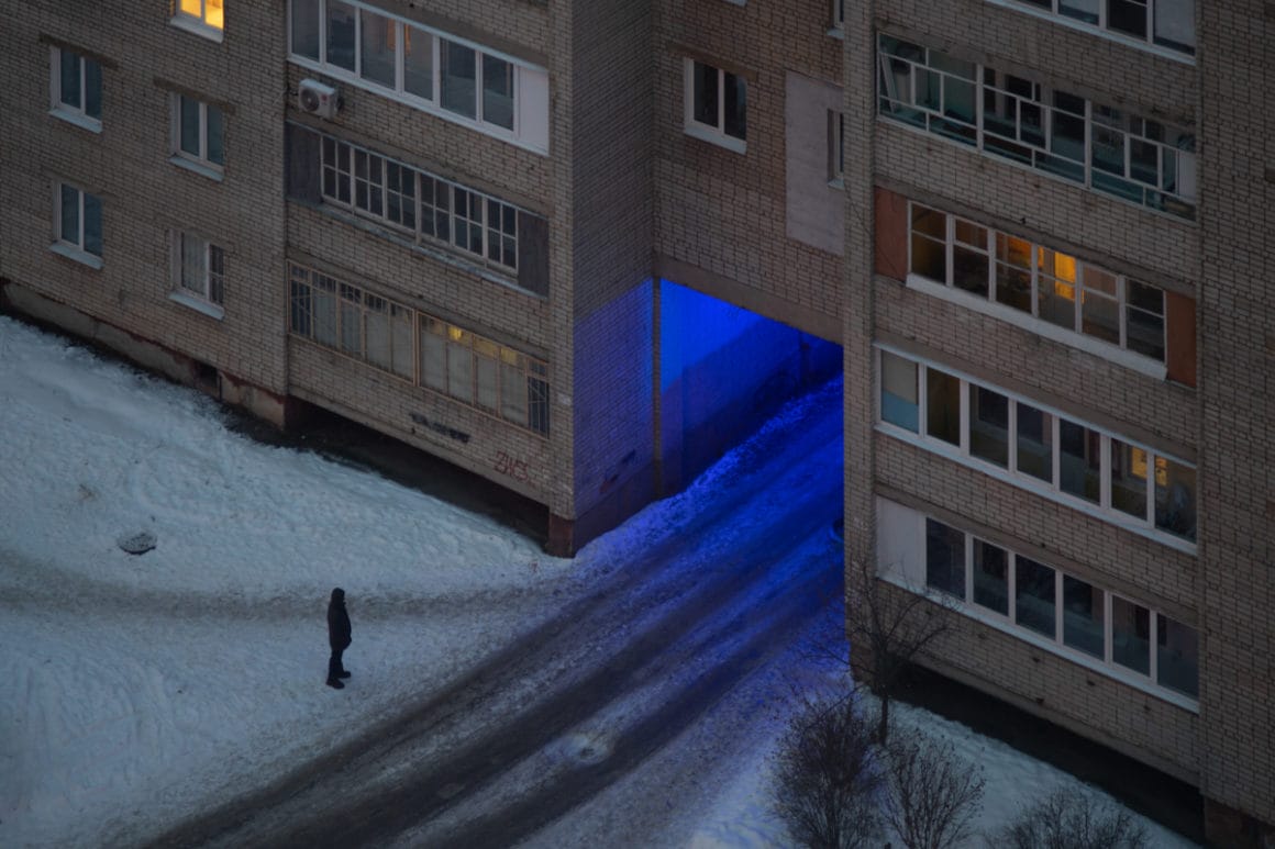 un individu se trouve devant l'entrée d'immeubles éclairés de bleu