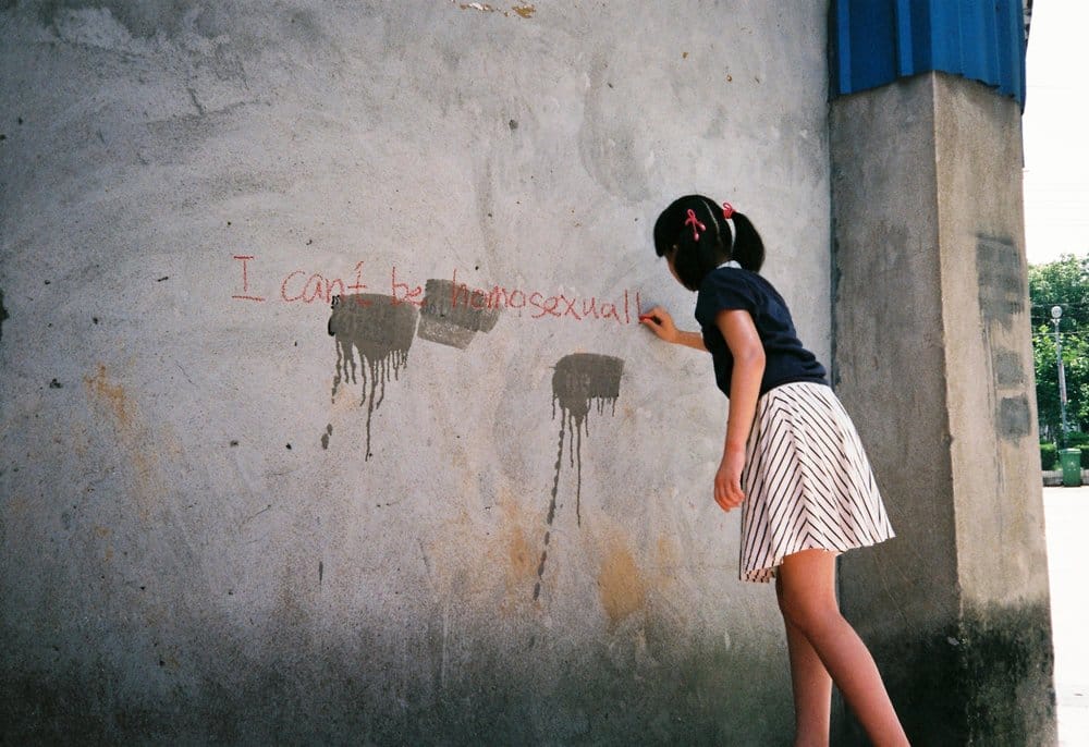 photo d'une petite fille écrivant I can't be homosexual sur un mur