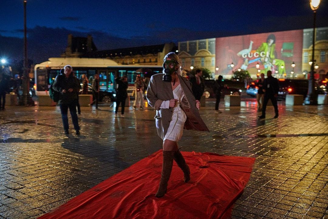 Un femme portant un masque à gaz sur un tapis rouge devant le louvre