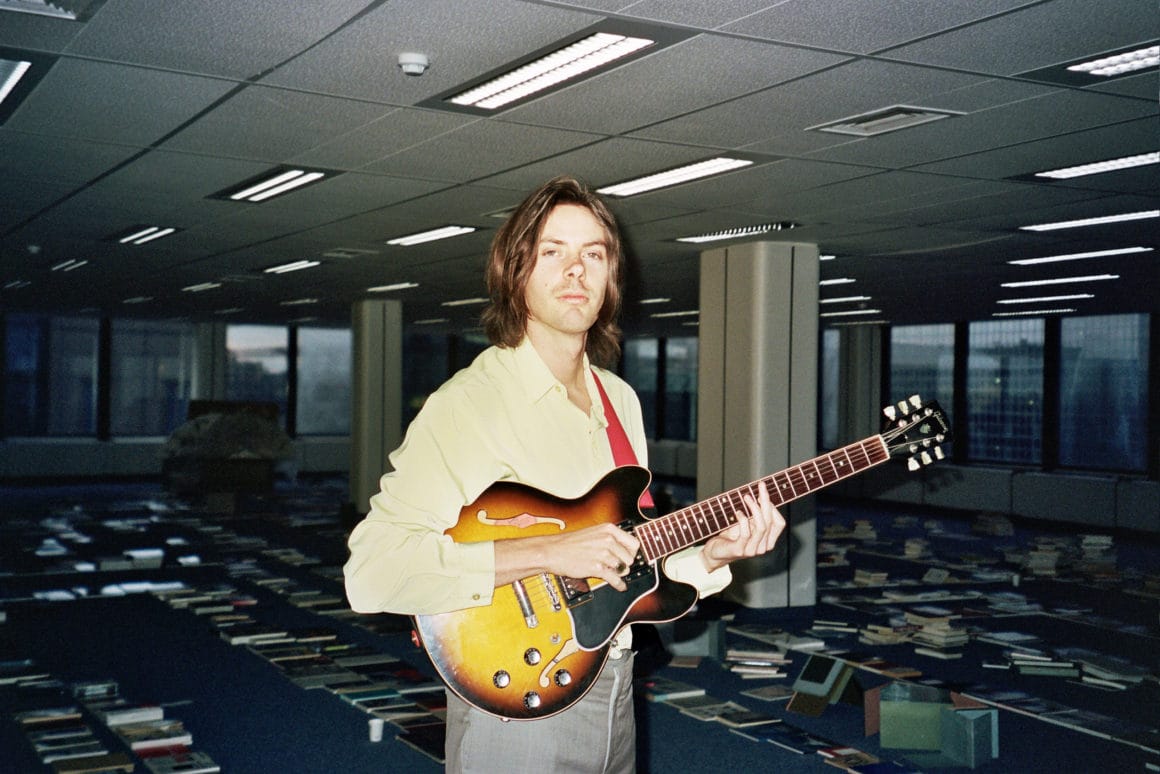 Robbing Millions pris en photo avec sa guitare au flash dans ce qui semble être des bureaux