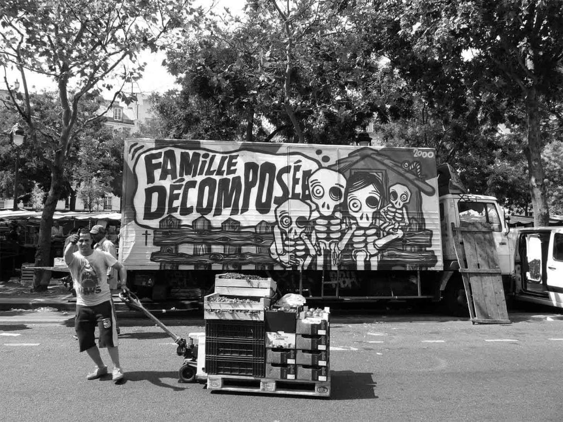 On voit un camion ornementé d'un graffiti du peintre Mygalo sur une place de marché