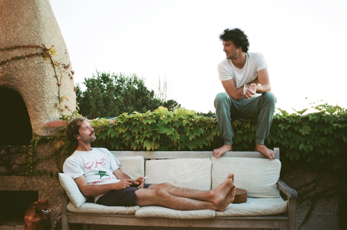 Photographie argentique des deux musiciens d'Entrée Libre. Le premier est installé confortablement sur un canapé d'extérieur, le second est installé un peu plus haut et lui parle.