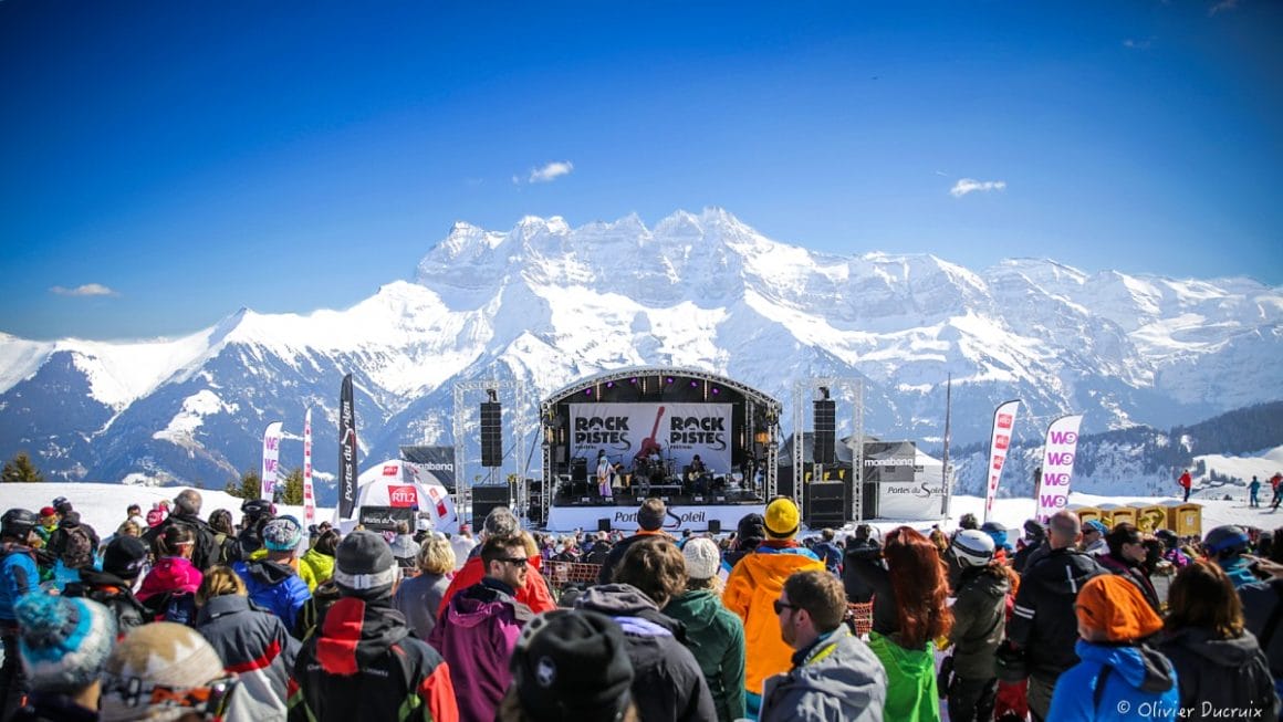 Image du festival Rock sur Piste avec la scène et le public devant. En fond on voit la chaîne de montagnes appelée les Dents du Midi.