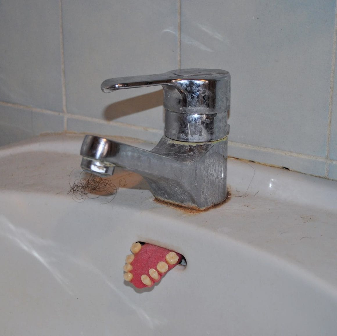 Sculpture d'une langue avec des dents sortant d'un lavabo