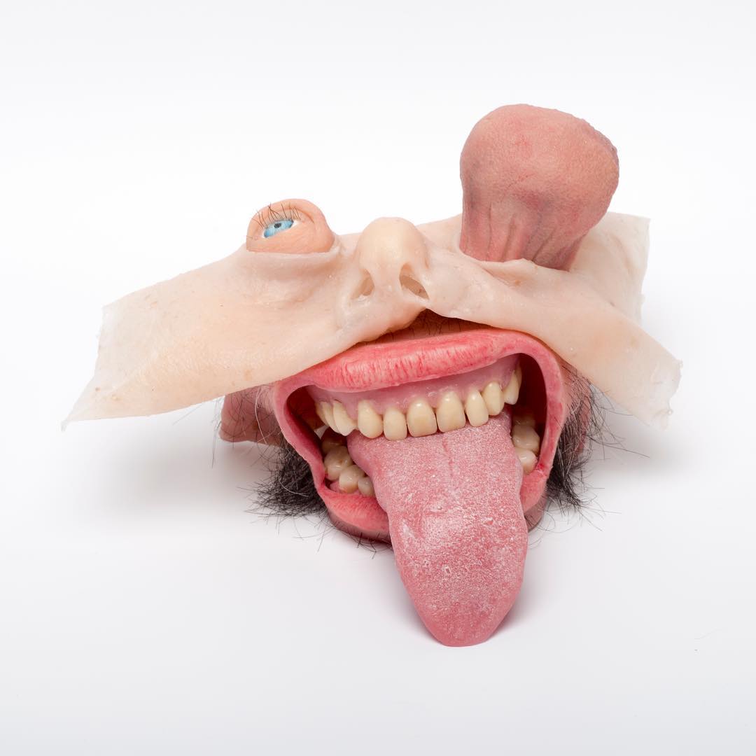 Sculpture d'un visage réduit à la bouche avec une langue tirée, des yeux sortant des orbites 