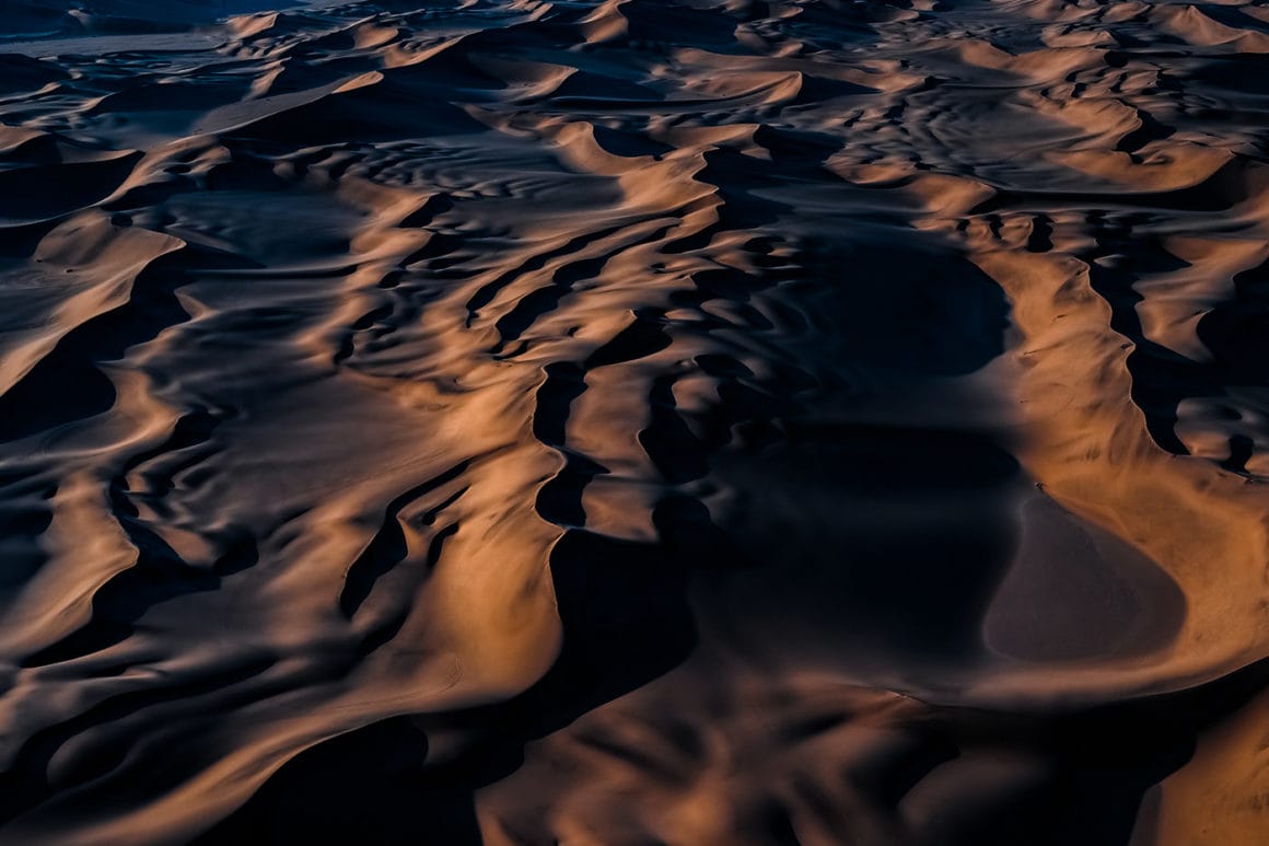 Les dunes de sable de Namibie forment des vagues lisses et gracieuses sous le soleil couchant