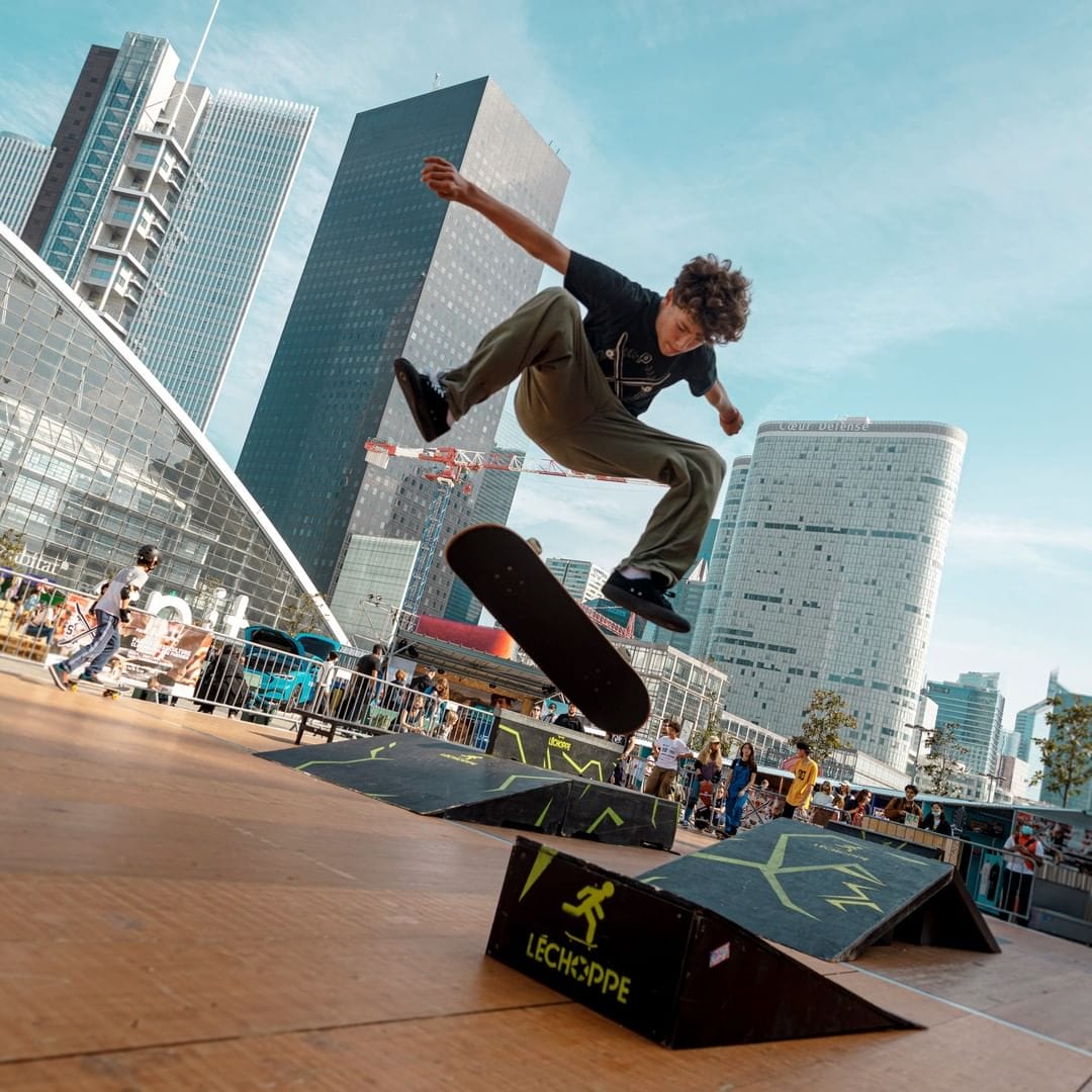 Sur La Défense à paris, un jeune homme fait une figure de skate