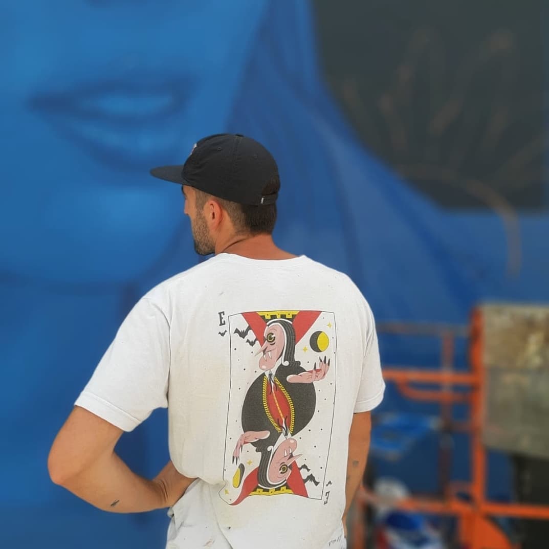 L'artiste Mr.sor2 se tient de dos avec un t-shirt représentant une dérivée d'une carte de jeu 